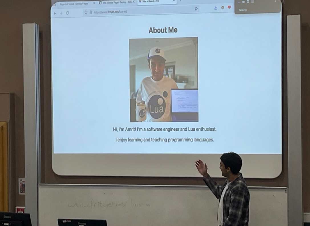 An image of one of Amrit's slides for his Lua Workshop, which contains an image of him with a Lua cap, a Lua shirt, a
Lua mug and a laptop with Lua on it.